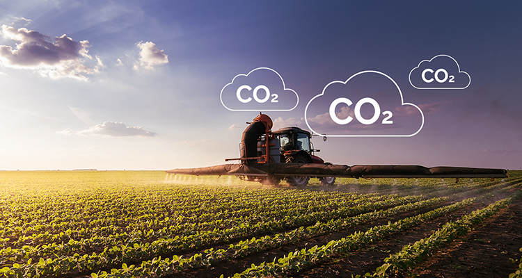 Máquina agrícola trabalhando em uma plantação, enquanto no céu há 3 siglas de CO2, responsável pelas mudanças climáticas